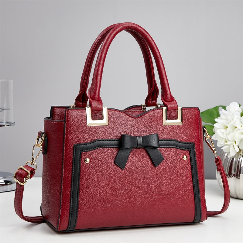 Red handbag with a black bow on a light gray background